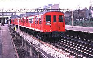 A three-quarter photograph of a red train with sliding doors and flared sides.