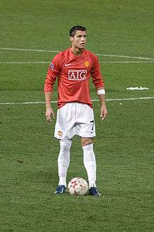 Cristiano Ronaldo – wearing a long-sleeved red jersey, white shorts with a number 7 on the left-leg side and a white armband on the left arm – prepares to take a free kick.