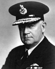 Portrait of man in dark military uniform with pilot's wings on chest, wearing peaked cap with two rows of braid
