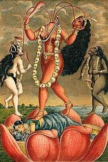 A decapitated, nude, fair goddess stands on a copulating couple inside a large lotus. She holds her severed head and a scimitar. Three streams of blood from her neck feed her head and two nude (one white, another black coloured) women holding a knife and a skull-cup, who flank her. The goddess wears a skull-garland, a serpent (across her chest) and various gold ornaments.
