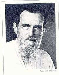  Black and white profile photograph of an old man in white beard and dark hair.
