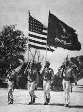 Color guard of four Filipino men wearing World War II United States Army Uniform; the national colors and regimental colors in the center.