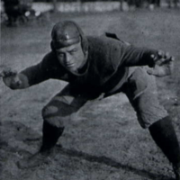 Football player in uniform, crouching with arms and legs spread