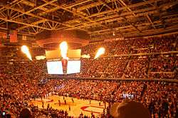 Indoor arena with people lighted by fire.