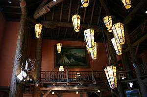 Interior of the great room in the Lake McDonald Lodge, showing unique chandeliers, massive rough wood construction, and mounted animal heads.