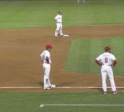 Runners on second and third base, with the third-base coach nearby
