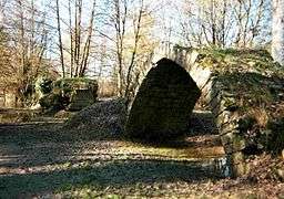 View of the ruined arch of a bridge isolated in a meadow