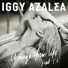 A black-and-white portrait of a young woman with wet, blond hair wearing a chain-mail bikini striking a dramatic pose. Centred across in white cursive font stands "Change Your Life Feat. T.I". Above the woman in white bold font stands the name "Iggy Azalea".