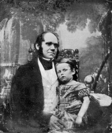 Darwin in his thirties, with his son dressed in a frock sitting on his knee.