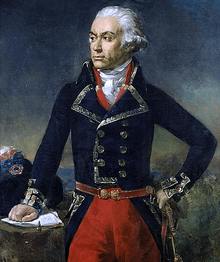 Painting of a determined-looking man who is standing with his left hand on his hip and his right hand on a table. He wears a dark blue double-breasted military coat with red breeches. His hair or wig in the style of the late 18th century, powdered white and curled at the ears.