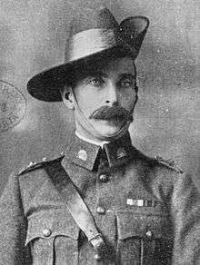 Head and shoulders view of man with large moustache in uniform, with Sam Brown belt, rising sun badges on his collars, and a slouch hat, turned up on the left side. He wears two ribbons on the left breast.