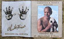 Left panel shows two hand prints, handwritten name Chester Himes, and block text "Missouri USA, Moraira."  Right panel shows bust of muscular shirtless man with little hair, graying mustache, bare chest, dark skin, holding siamese cat.  Italic text is "created by R. Mendorfer & Paco."