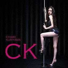 A long haired woman wearing a short black dress and high heels holds a dance pole, and wraps her left leg around the pole. The background is a dark stage, and there is pink font saying "Chiaki Kuriyama" in small letters, and "CK" in large letters.