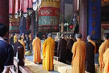 Buddhist monks in saffron robes standing performing a ceremony in Hangzhou, China