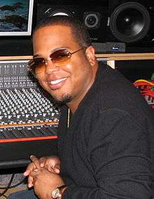 An African-American man wearing orange sunglasses and black T-shirt is smiling.