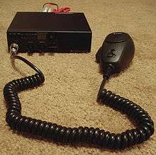 Small black mobile radio with hand-held microphone and long, coiled mic cord
