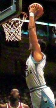 A basketball player slam dunking the ball.