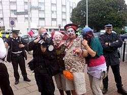 Three protesters dressed as clowns posing with a FIT photographer. Other officers are stood around smiling