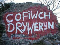 a ruined wall, splashed with red paint, upon which in white paint is written the words 'cofiwch Dryweryn'