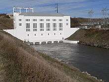 Hydropower plant with tailrace canal running out of base; transformer substation on bank