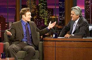 Late-night talk show hosts Conan O'Brien, left, and Jay Leno, right, talk on the set of The Tonight Show years prior in 2004.