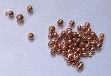 Several dozen metallic pellets, reddish-brown. They have a highly polished appearance, as if they had a cellophane coating.
