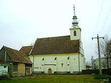 A small church with a tower and a nearby small wooden building