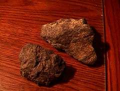 Two rough chunks of cumberlandite showing reddish brown coloring with a few whitish streaks.