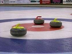 two yellow and one red curling stones on red, white and blue ice