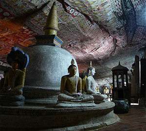 Stupa and statues of bodhisattvas inside a cave.
