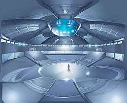 Drawing of a large, enclosed, futuristic arena with a man standing at the centre; large ramps lead to galleries above.