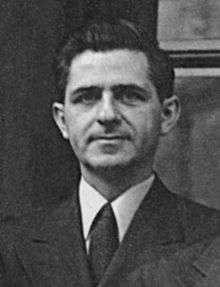 Black and White head and shoulder shot of 30's white male with thick black hair, and a three piece suit from the 1940s