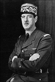 Charles de Gaulle seated in uniform looking left with folded arms