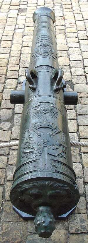 Photo shows a cannon whose barrel is decorated with designs and inscriptions.