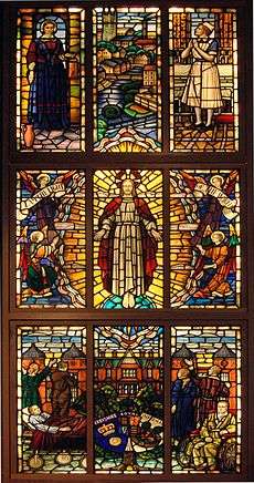 A vertical rectangular stained glass window with nine panels, each holding one or more human figures