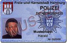 A identity card with a picture, the coat of arms of Hamburg, the police star of Hamburg and the German word sample written across.