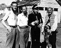 1948 B&W photograph of Donn Reynolds (far left) on the film set of Eureka Stockade standing with Peter Finch, Grant Taylor, and Sid Hermann (New South Wales, Australia).