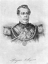 Lithograph depicting head and shoulders of a man with gray moustache wearing a military tunic with epaulettes and elaborate lanyards, several medals at his neck and breast, sash of office, and a prominent star on a heavy gold chain suspended from his shoulders