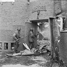 Two men outside a shot and bombed building