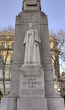 A marble statue of Edith Cavell in nurse's uniform backed by a large granite column