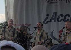 A three men are singing with a musicians playing in the background