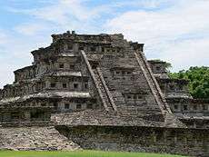 Ruins of a stone pyramid with about five levels. Each side of a step contains niches.