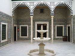 Patio du Petit Palais avec une fontaine de marbre au milieu de la cour et une colonnade.