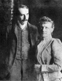 Nineteenth century photograph of a man in his 30s and a middle-aged woman standing side by side. He has a large moustache, and is looking at the woman; she is looking straight at the camera.