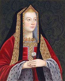 A blond woman with rosy cheeks holds a white rose. She wears a gilded black shawl over her head, and a red robe trimmed in white spotted fur.