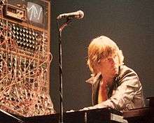 Keith Emerson performs with a complex synthesizer system that is barely visible through a mass of cables that connect its various modules