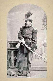 Joshua Norton in full military regalia with his hand on the hilt of a ceremonial sword.