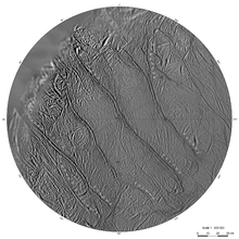 A circular part of a grayish surface, which is intersected from the top-left to the bottom-right by four wide sinuous groves. Smaller and shorter grooves can be seen between them running either parallel to the large grooves or criss-crossing them. There is a rough terrain in the top-left corner.