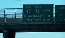 A green sign on an overpass reading end Interstate 80 begin Interstate 95 north George Washington Bridge New York City