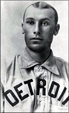 A man wearing a baseball jersey with a with "Detroit" written across the chest.